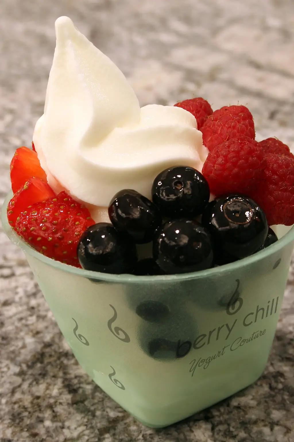 Cup of frozen yogurt topped with strawberries and blueberries