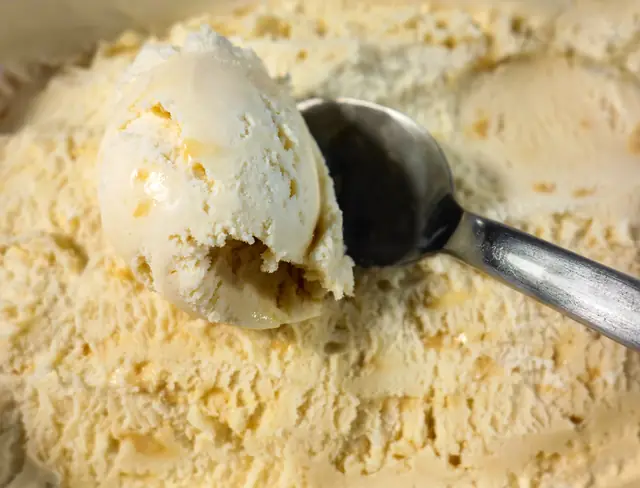 Scooping vanilla ice cream from a tub