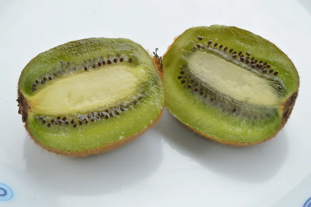 Kiwi fruits cut in half showing green flesh and black seeds, at a fruit stall in Howrah