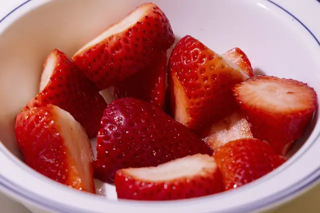 Halved fresh strawberries in a white bowl