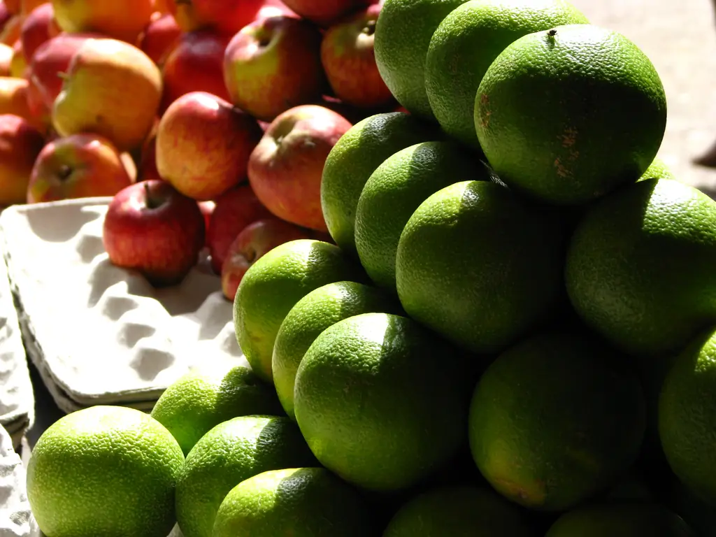 Green sweet lime (mosambi) and red apples stacked at Koyambedu wholesale market, Chennai